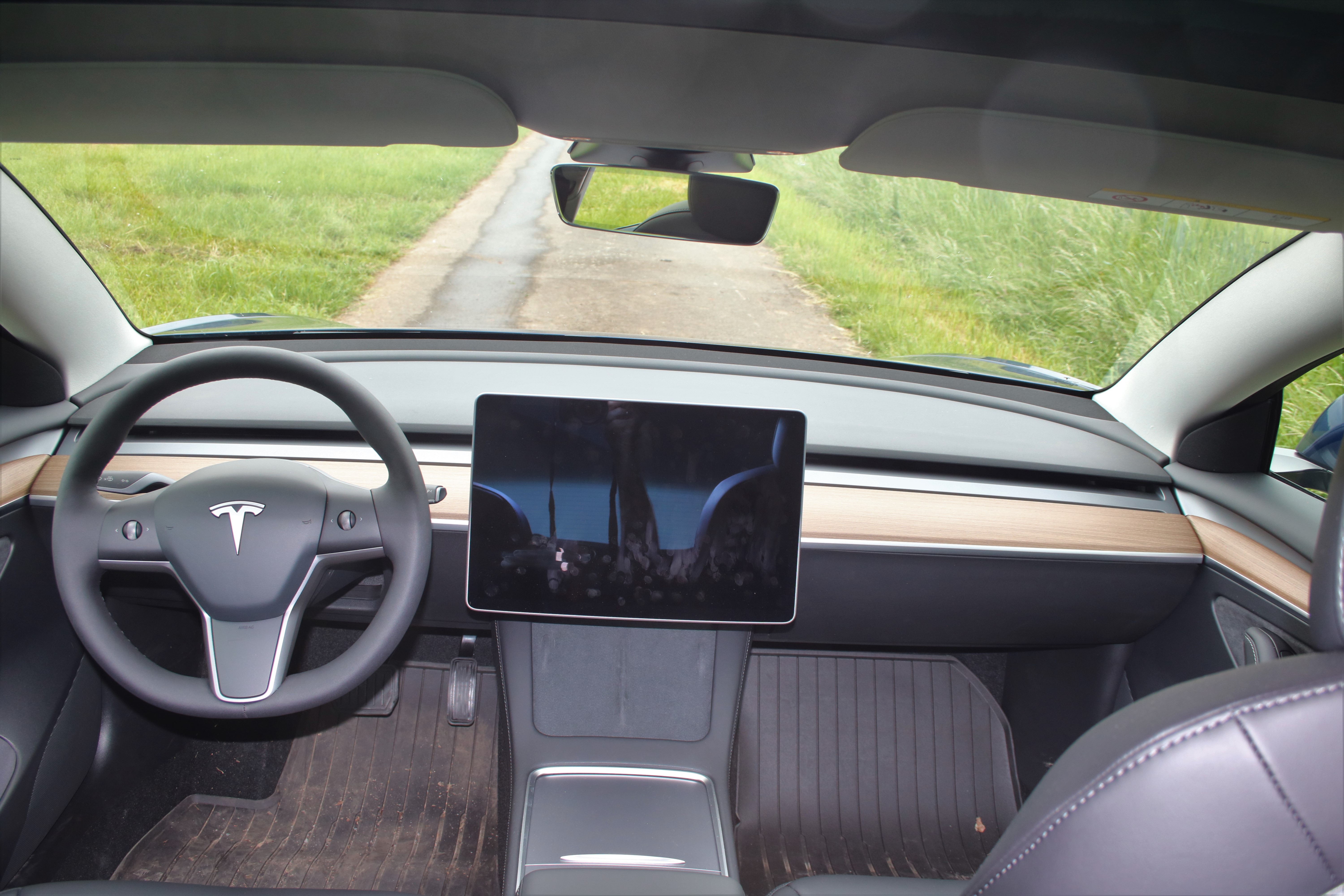 Салон Tesla Model 3 refresh 2021 с левым рулём, двумя подрулевыми рычагами и обновлённой центральной консолью.