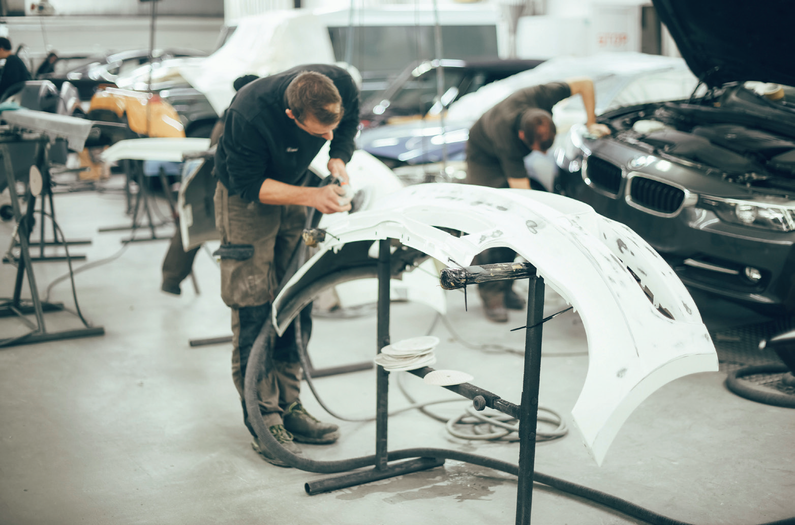Technicians working on a body panel inside the Atelier N°1 workshop, part of the Louyet group.