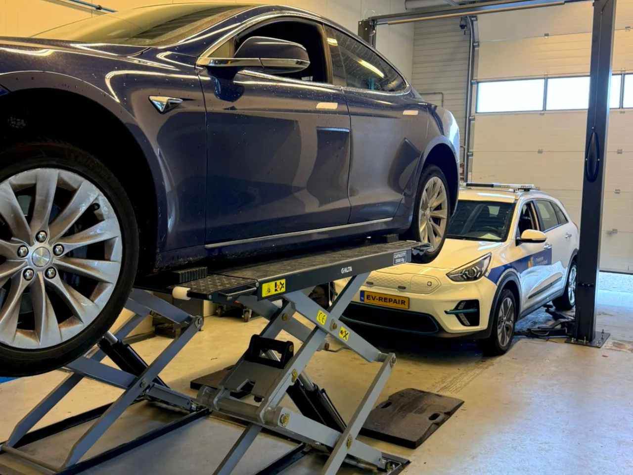 Tesla на подъёмнике в мастерской EV-REPAIR в Велсербруке.