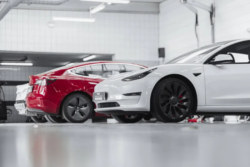 Два автомобиля Tesla в ремонтном помещении на фотографии EV Tesla Service.
