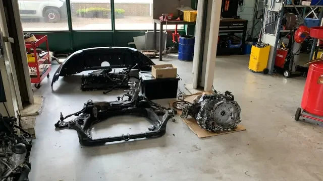 The MTechniek workshop work area, with vehicle components disassembled.