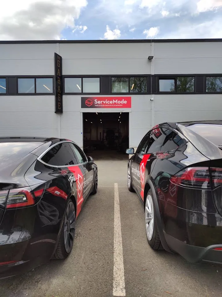 Фасад мастерской ServiceMode в Пеэтри; перед въездом стоят фирменные автомобили Tesla, фото мая 2025 года.