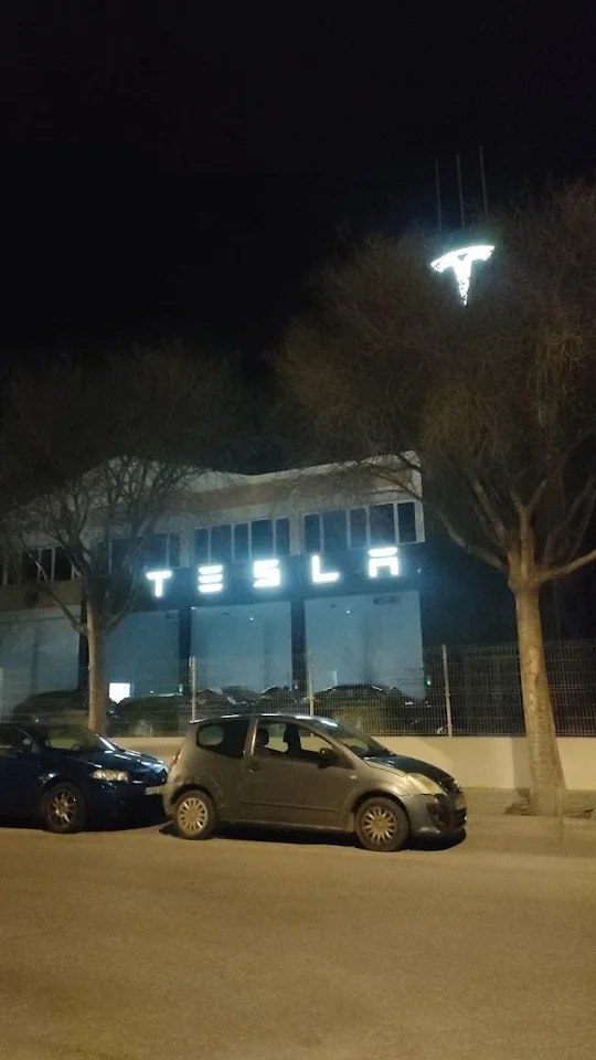 Внешний вид Tesla Center Mallorca с фирменной вывеской и автомобилями у входа.