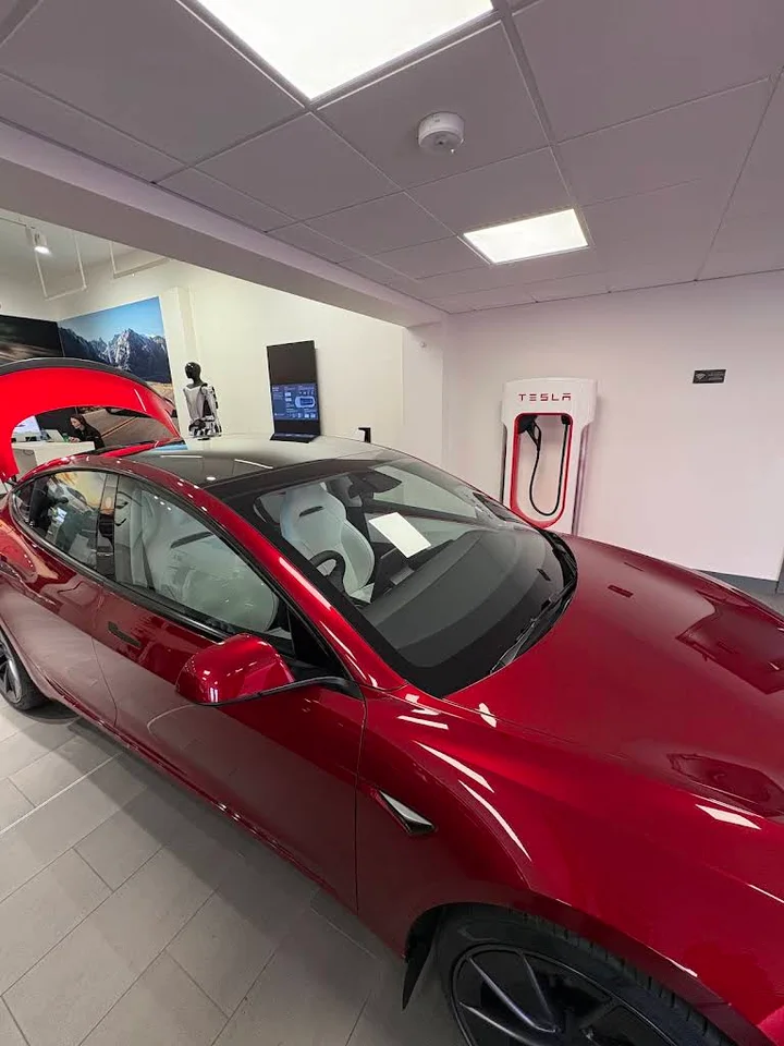 Красная Tesla в помещении Tesla Centre Dublin рядом с зарядной стойкой, Сэндифорд.