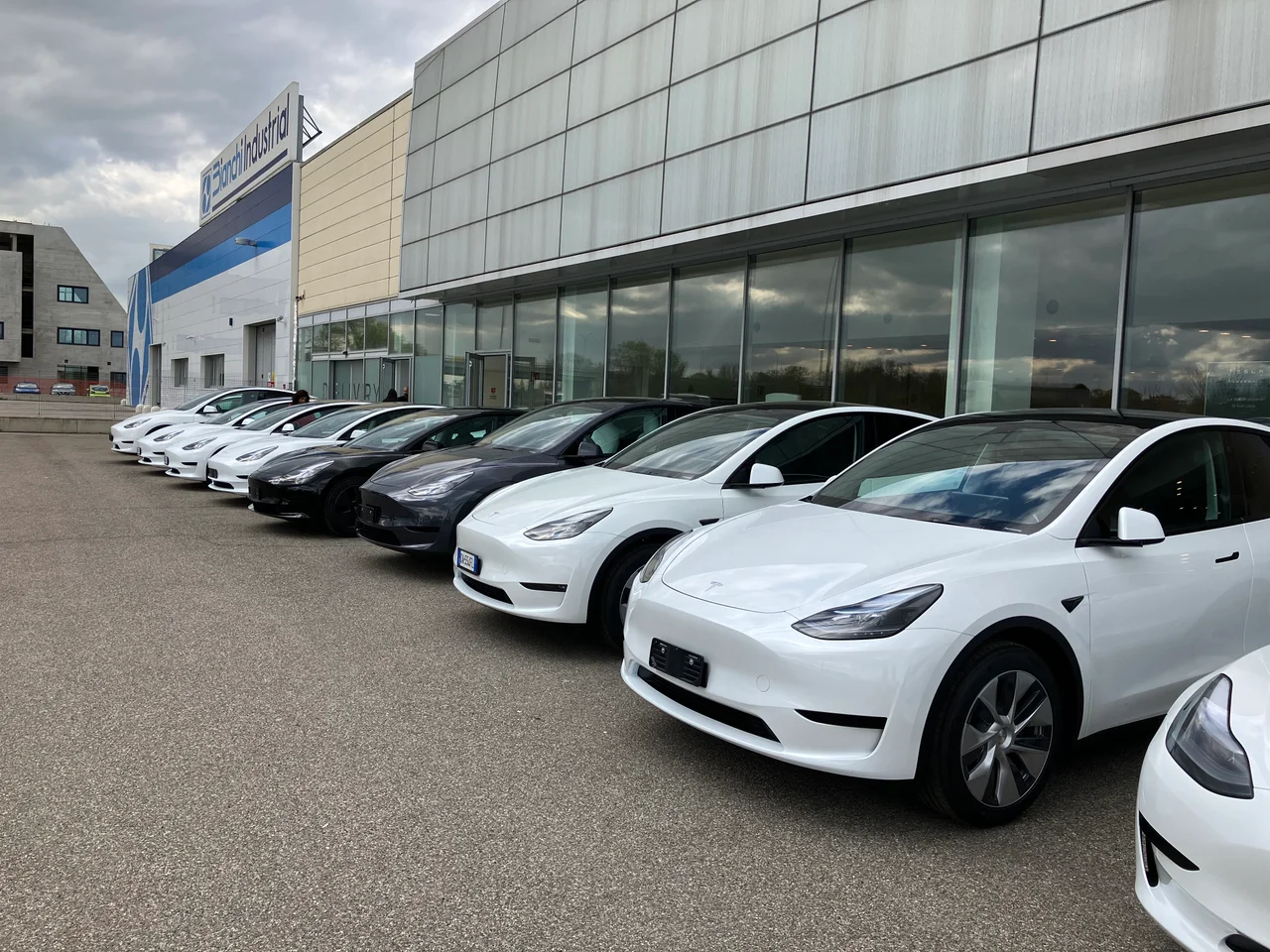 Автомобили Tesla у стеклянного фасада Tesla Center Bologna по адресу Via Giovanni Elkan 3. Снимок апреля 2023 года.