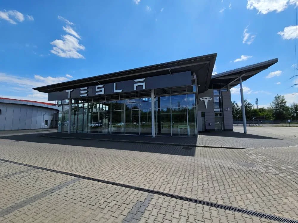 Фасад Tesla Center Katowice по адресу al. Walentego Roździeńskiego 208; сервисный профиль Tesla Service Katowice указан в том же месте.