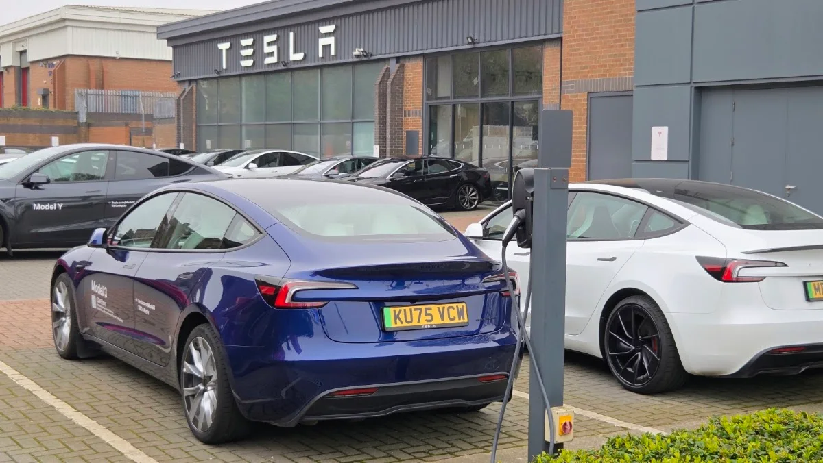 Вход в Tesla Centre Leeds и автомобили на площадке перед центром.