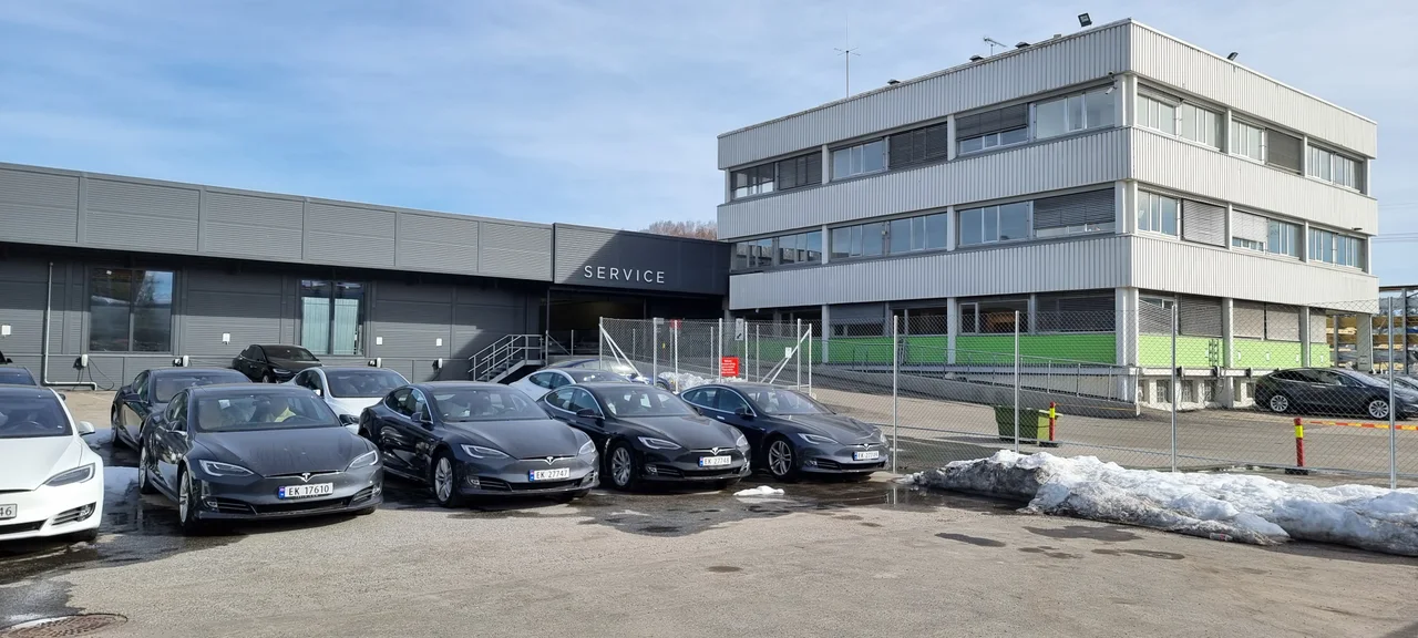 Tesla Service Oslo – Karihaugen: сервисный корпус с табличкой SERVICE и рядом припаркованные автомобили Tesla. Снимок марта 2021 года.