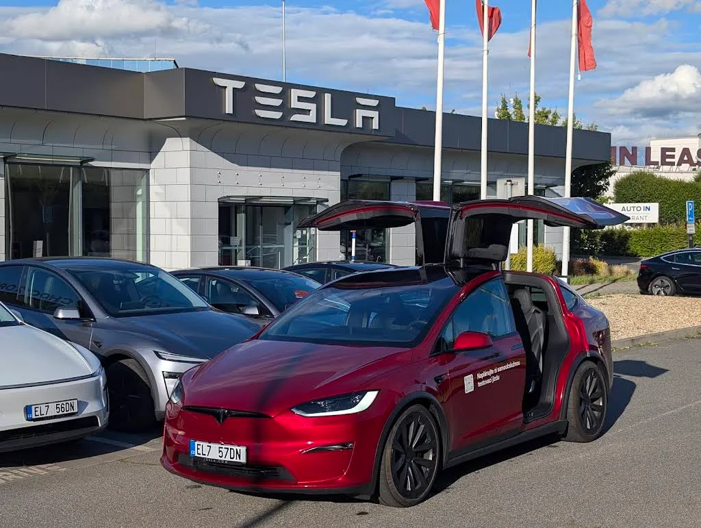 Фасад Tesla Center Praha с фирменным логотипом и автомобилями перед зданием; фото июля 2025 года.