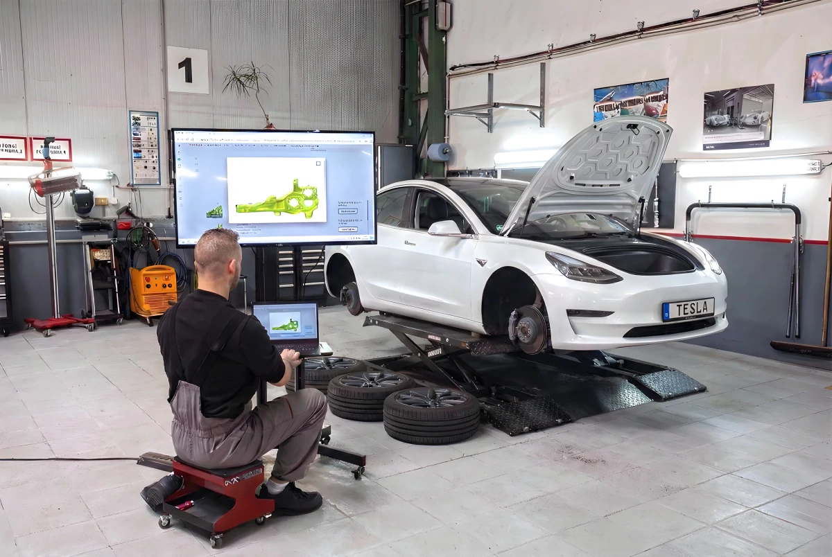 Специалист Torera работает с Tesla Model 3 в мастерской в Праге.
