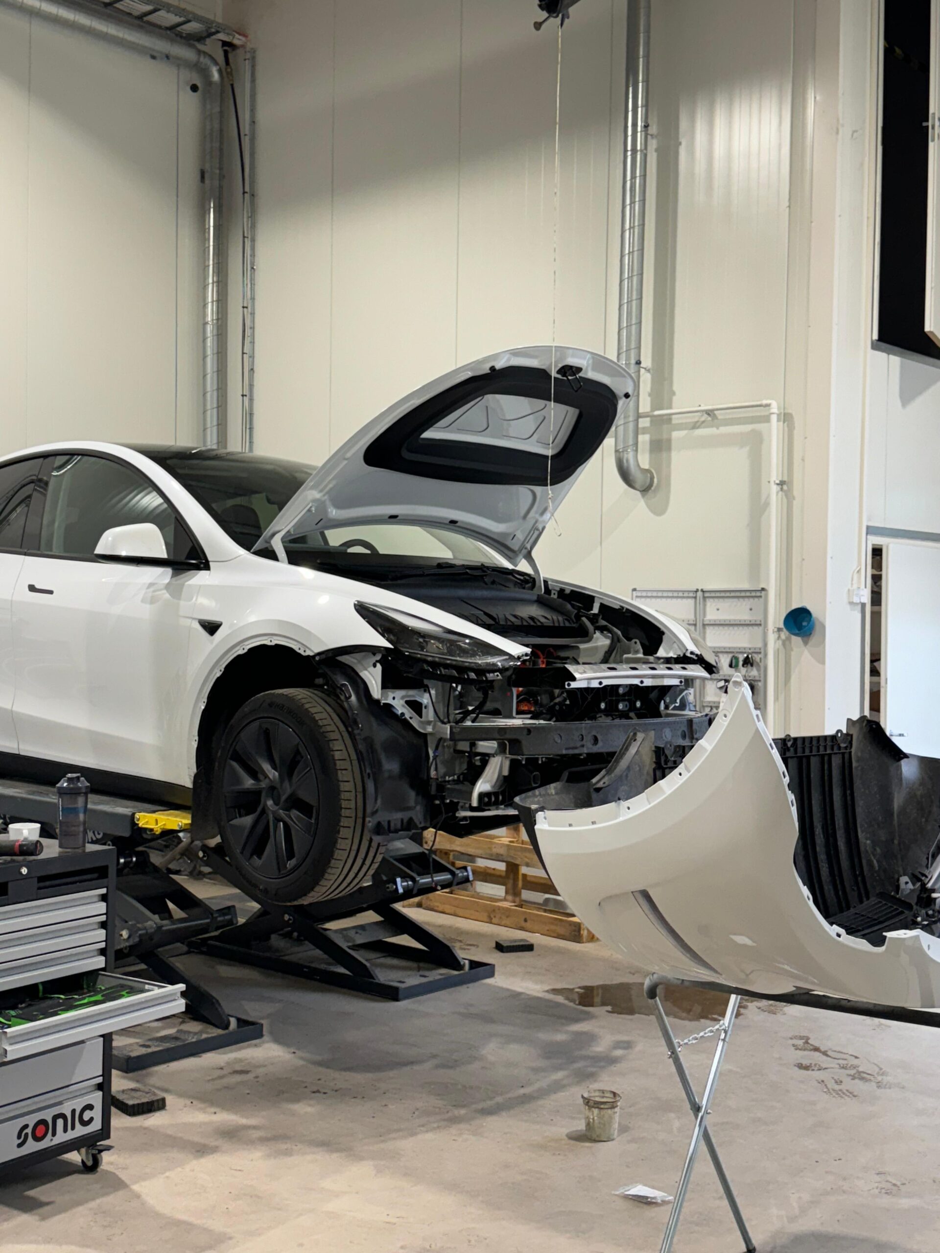 Tesla Model Y в кузовной мастерской Vaurioturva Malmi во время ремонта.