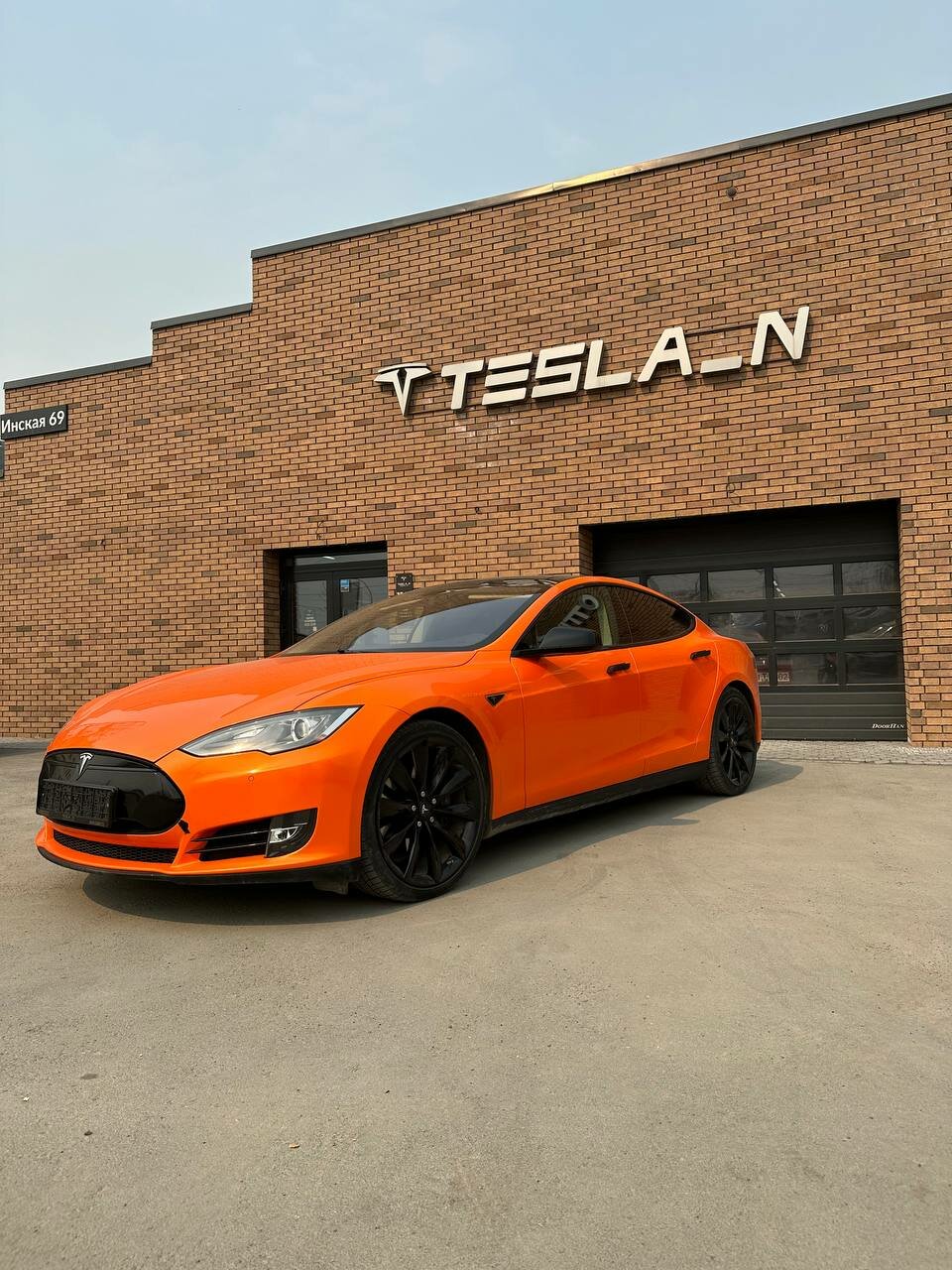 Фасад Tesla_N на Инской, 69, и оранжевая Tesla перед входом