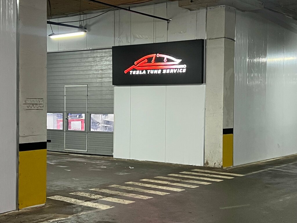 Фирменная вывеска TESLA TUNE SERVICE в помещении мастерской.