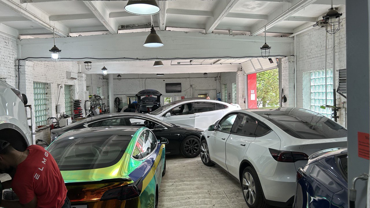 Электромобили Tesla внутри мастерской ELMOB; на футболке сотрудника видна надпись ELMOB.