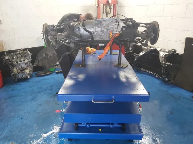 Снятый автомобильный агрегат на подъёмном столе в мастерской Independent Tesla Specialists.