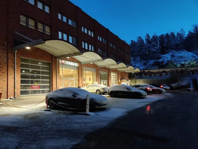 Vintervy av Tesla-servicecentret på Kanalvägen 16 med infartsgrindar och parkerade bilar.