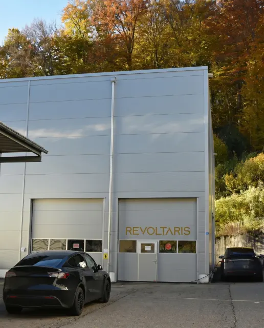 Bâtiment de l’atelier Revoltaris à Stallikon avec des Tesla devant l’entrée.