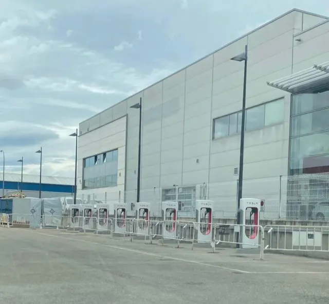Fila de puestos de Supercharger de Tesla junto al edificio del centro de servicio en Fuenlabrada.