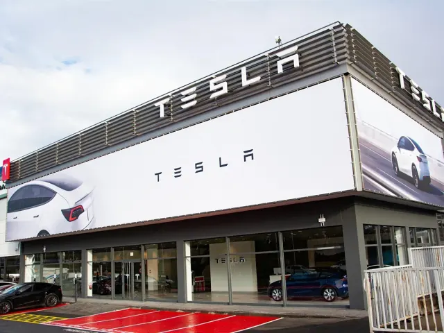 Exterior del Tesla Center de Iurreta, con el letrero de Tesla y automóviles aparcados delante.
