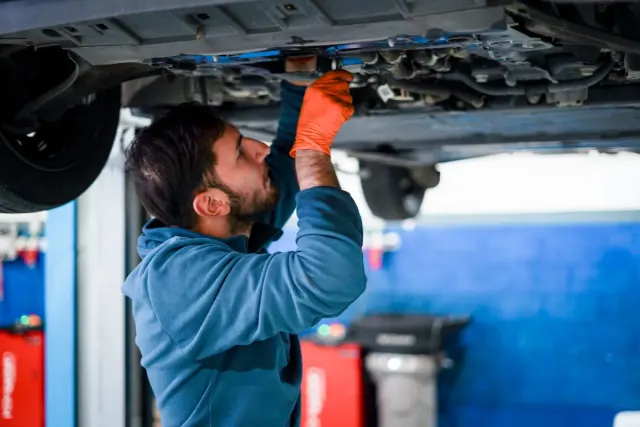 Um mecânico inspeciona um automóvel num elevador na oficina LHSAuto, em Coimbra.