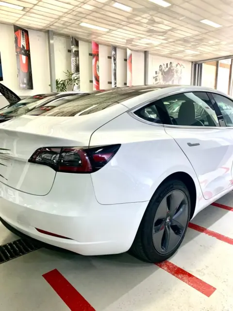 Um Tesla Model 3 branco no interior da oficina Auto Mecânica do Monte.