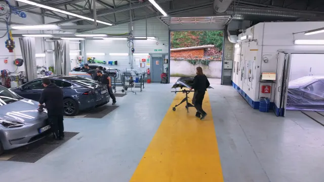 In der Berliner Werkstatt Süß arbeiten Techniker an einem Tesla im Karosseriebereich.